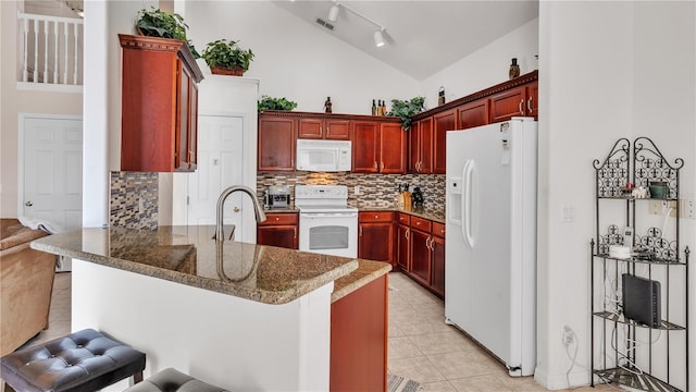 kitchen featuring kitchen peninsula, white appliances, track lighting, high vaulted ceiling, and tasteful backsplash