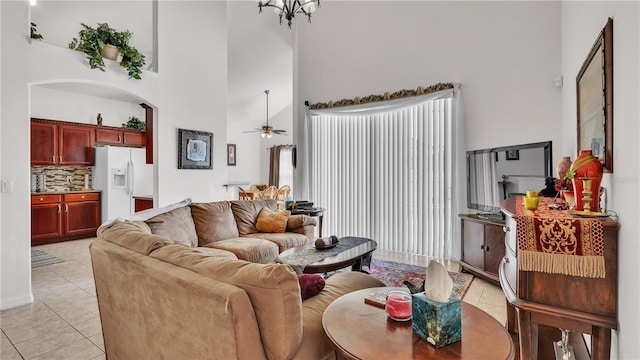 living room featuring light tile floors, high vaulted ceiling, and ceiling fan with notable chandelier