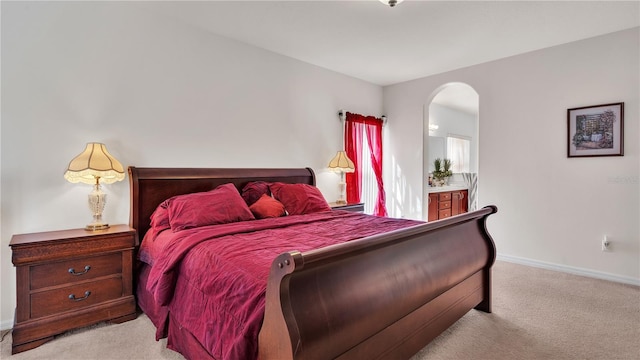 bedroom featuring light carpet and ensuite bath