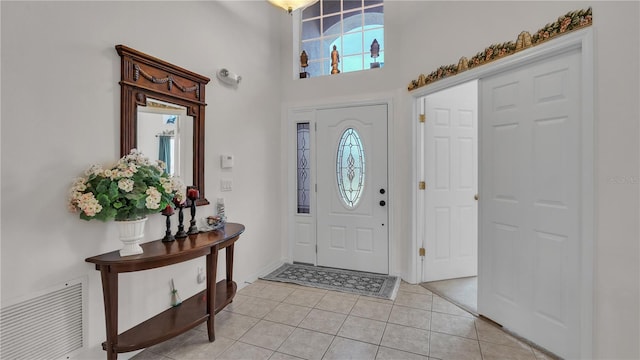 entryway with plenty of natural light, a high ceiling, and light tile floors