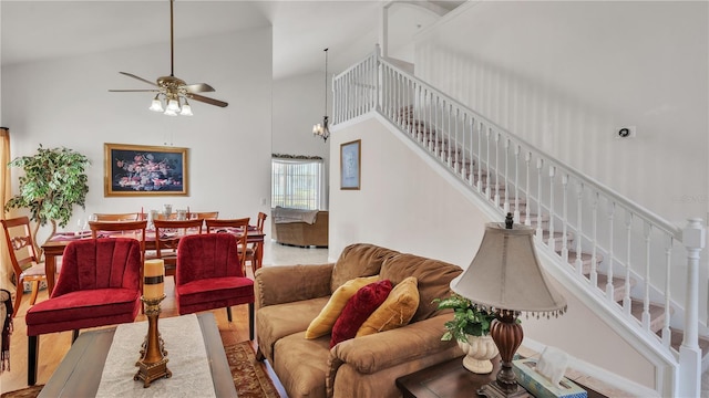 living room with high vaulted ceiling, ceiling fan with notable chandelier, and light hardwood / wood-style flooring