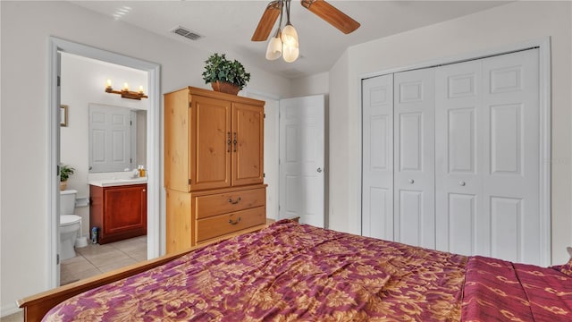 bedroom with ceiling fan, light tile floors, sink, ensuite bath, and a closet