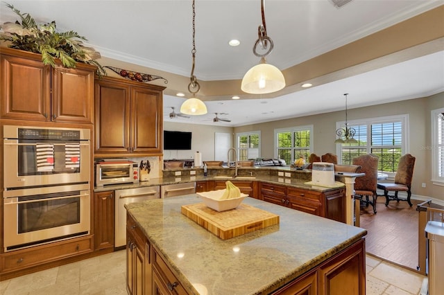 kitchen featuring a kitchen island, decorative light fixtures, ceiling fan, and double oven