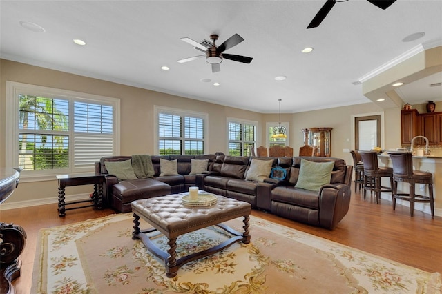 living room featuring ornamental molding, light hardwood / wood-style floors, ceiling fan, and sink