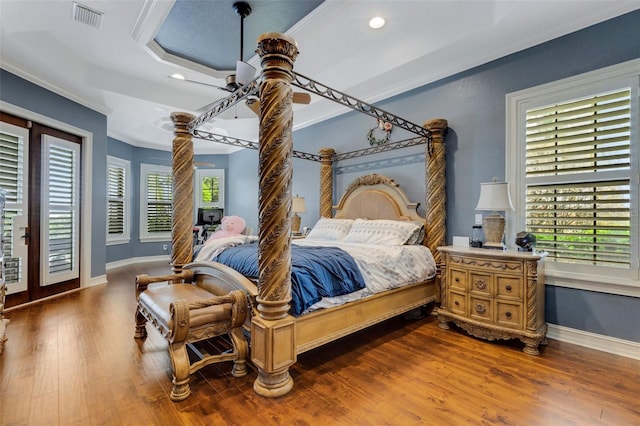 bedroom featuring a tray ceiling, access to exterior, dark hardwood / wood-style floors, ceiling fan, and crown molding