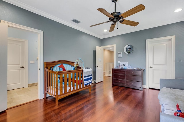 bedroom with dark tile floors, ornamental molding, ceiling fan, and a crib