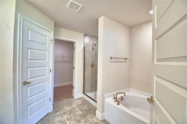 bathroom with a textured ceiling and independent shower and bath