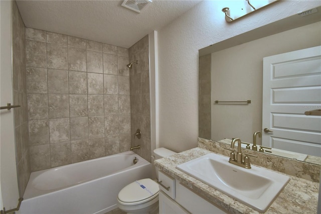 full bathroom featuring vanity, a textured ceiling, tiled shower / bath combo, and toilet