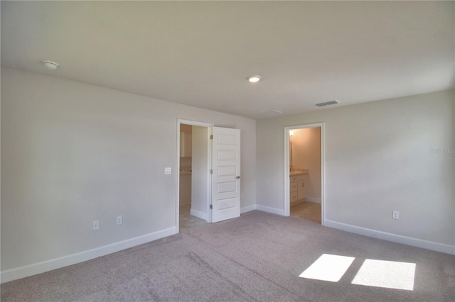 unfurnished bedroom with light colored carpet and ensuite bath