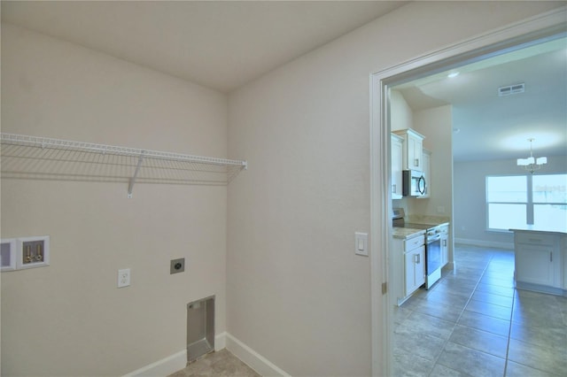 washroom featuring electric dryer hookup, light tile patterned floors, washer hookup, and an inviting chandelier