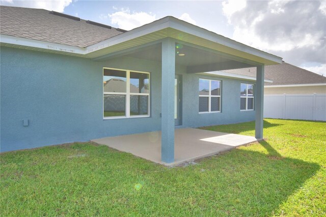 back of property with a lawn and a patio