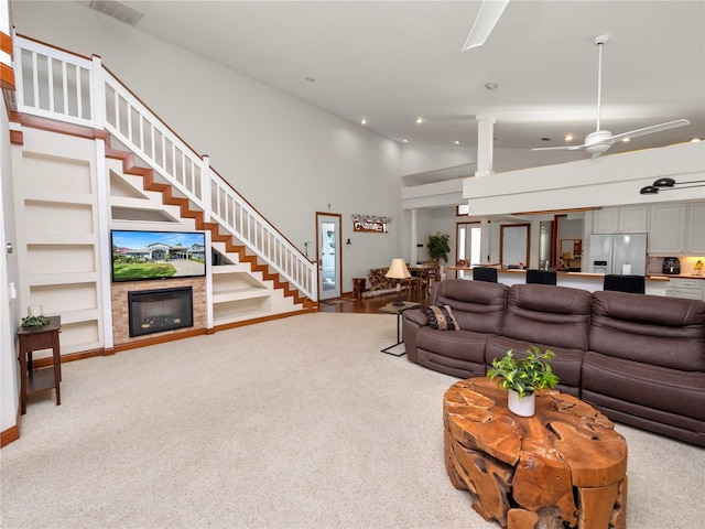 carpeted living room with built in features, ceiling fan, and high vaulted ceiling