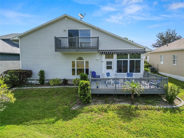 rear view of property with a balcony, a lawn, and a deck