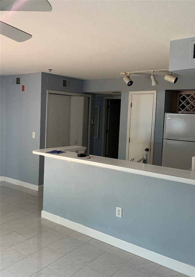 kitchen featuring rail lighting, ceiling fan, light tile flooring, and fridge