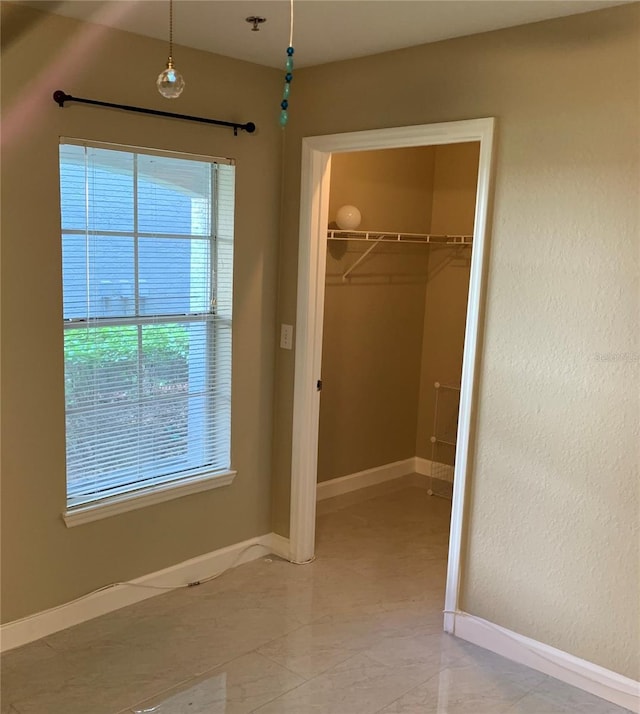 unfurnished bedroom with multiple windows, a closet, and light tile floors