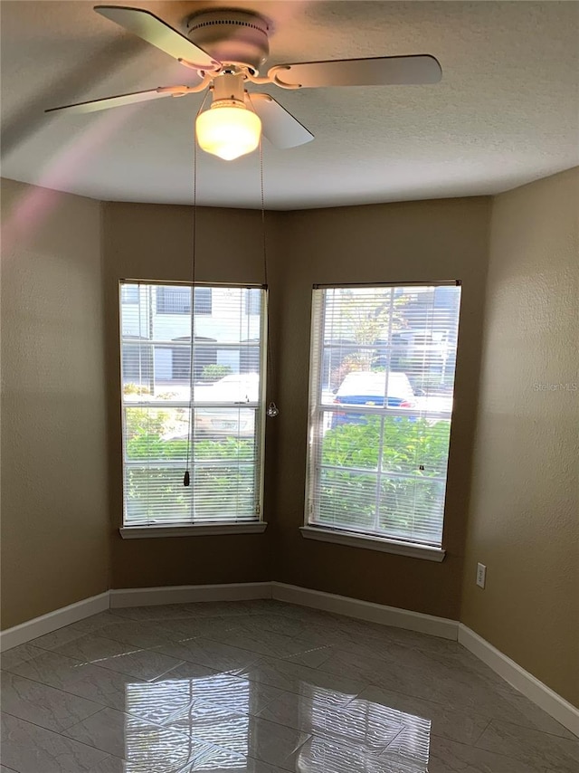 unfurnished room featuring dark tile flooring and ceiling fan