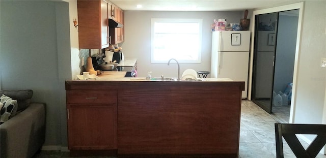 kitchen featuring sink, black range oven, white refrigerator, kitchen peninsula, and light tile patterned floors