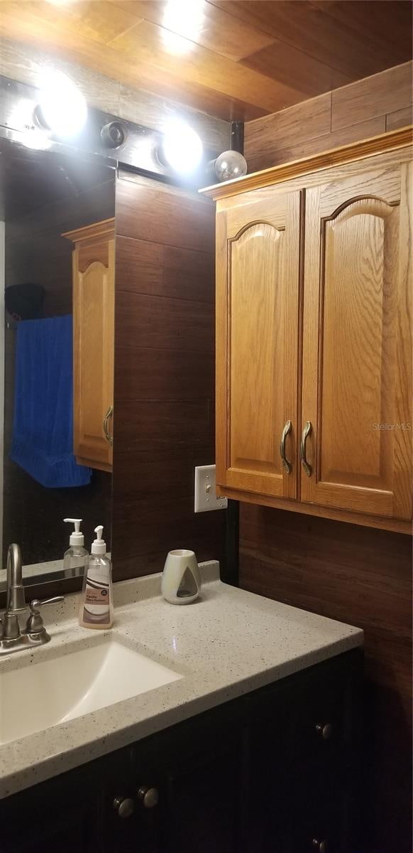 bathroom with wood walls, sink, and wood ceiling