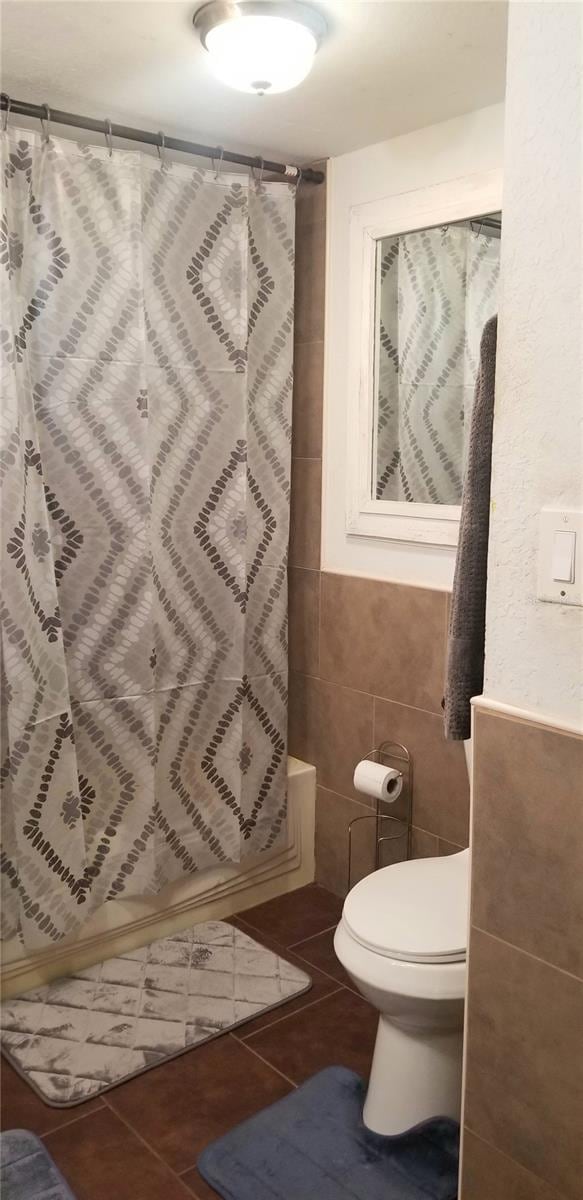 bathroom featuring tile patterned flooring, tile walls, and toilet