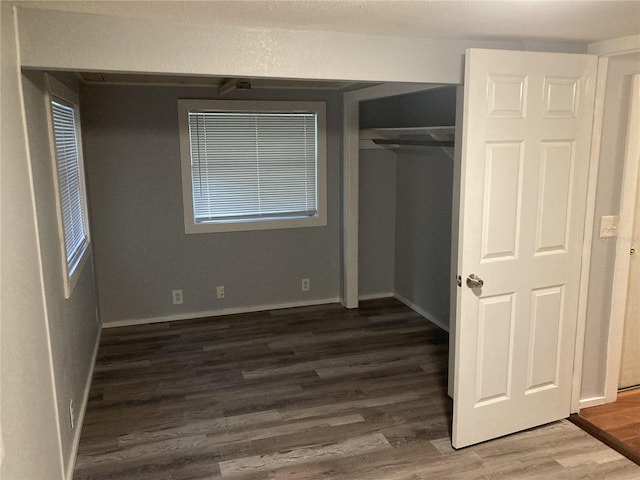 unfurnished bedroom with a closet and dark wood-type flooring