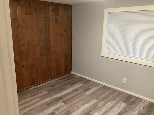 empty room featuring wood walls and hardwood / wood-style floors