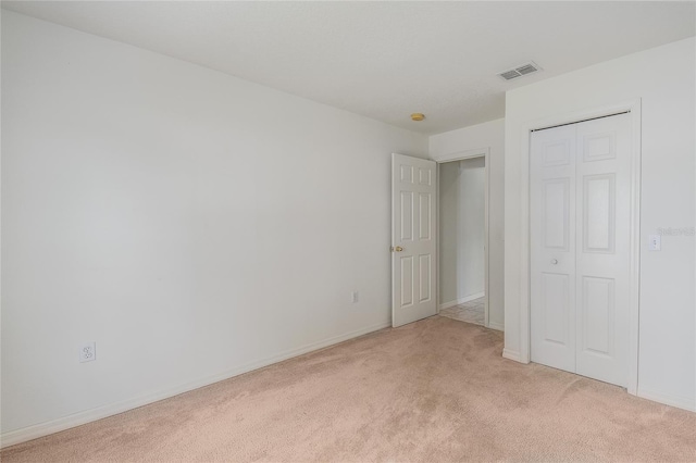 unfurnished bedroom featuring light colored carpet and a closet