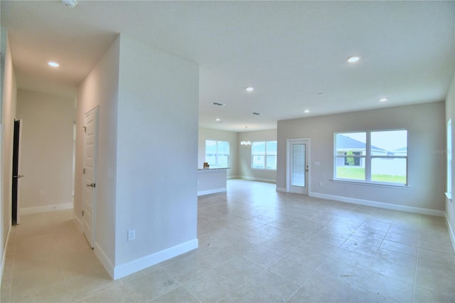 tiled empty room featuring a notable chandelier