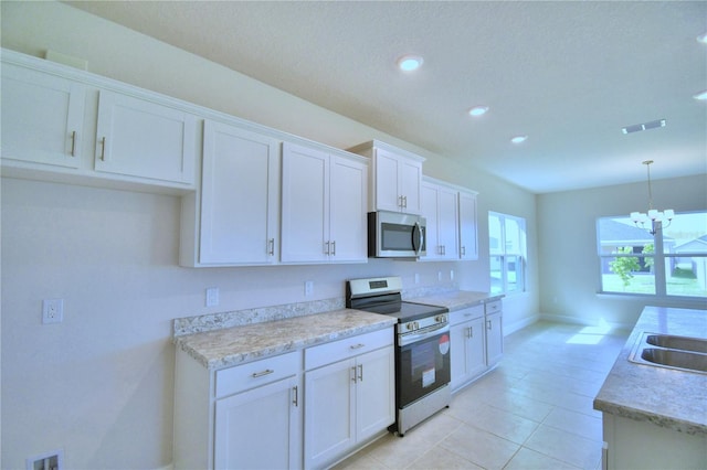 kitchen with light tile patterned floors, an inviting chandelier, pendant lighting, white cabinets, and appliances with stainless steel finishes