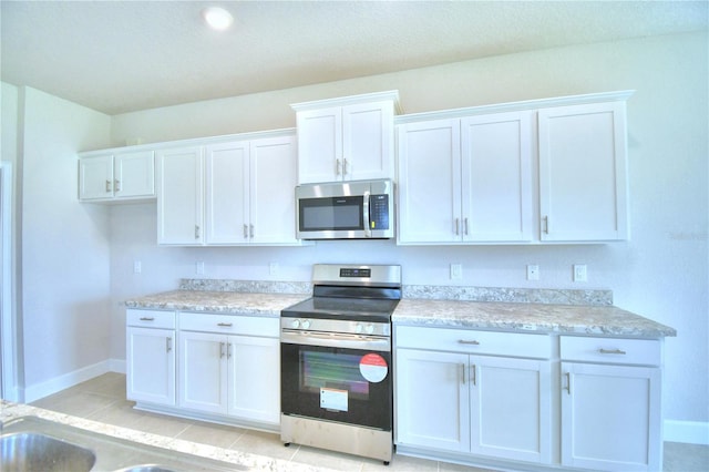 kitchen featuring sink, white cabinetry, stainless steel appliances, and light tile patterned floors