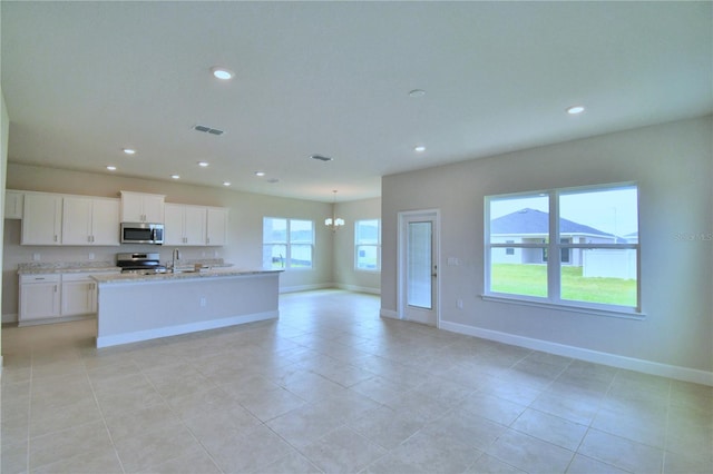 kitchen featuring white cabinets, a center island with sink, light stone countertops, stainless steel appliances, and a chandelier