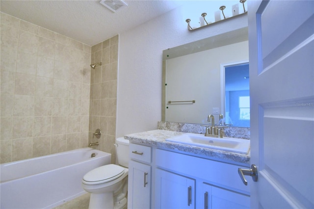 full bathroom featuring a textured ceiling, vanity, toilet, and tiled shower / bath