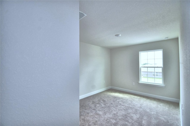 carpeted empty room with a textured ceiling