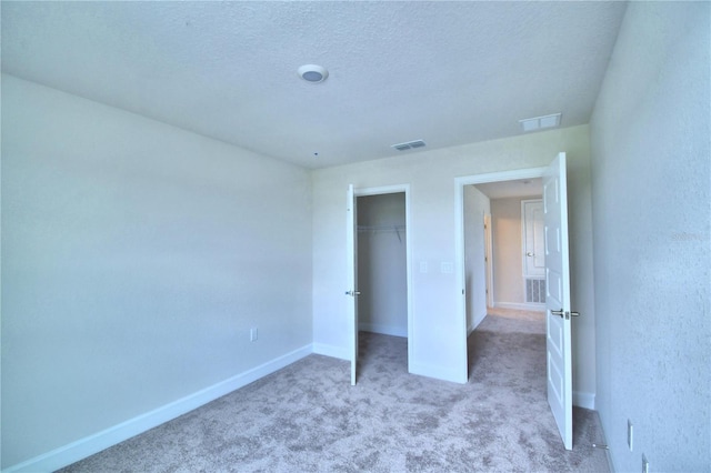 unfurnished bedroom with light colored carpet, a textured ceiling, and a closet