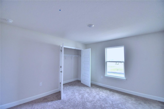 unfurnished bedroom featuring light carpet and a closet