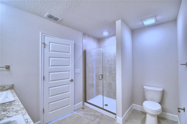 bathroom featuring tile patterned flooring, a textured ceiling, toilet, a shower with door, and vanity