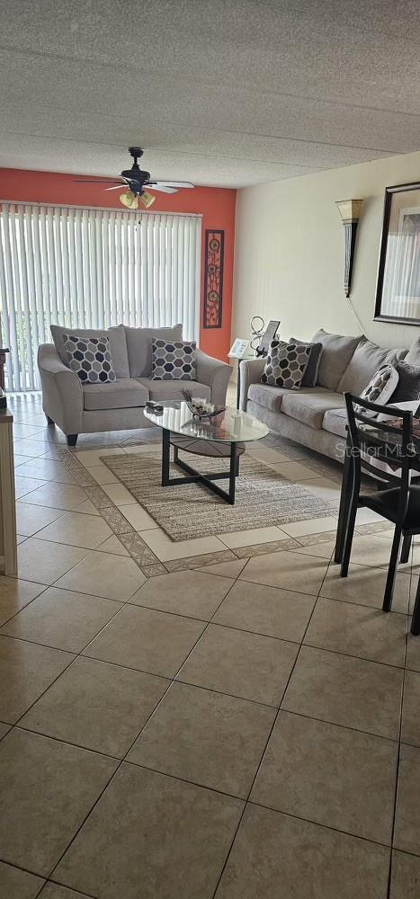 tiled living room with ceiling fan and a textured ceiling