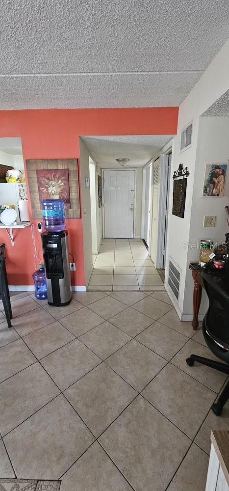 hall with light tile floors and a textured ceiling