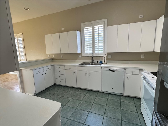 kitchen featuring white cabinets, dark tile flooring, white appliances, and sink