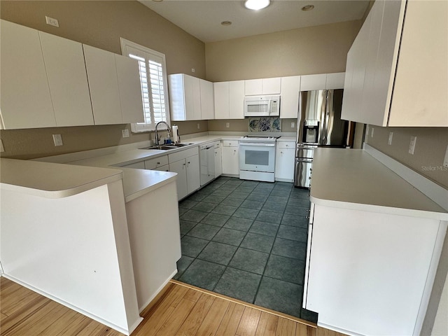 kitchen featuring white cabinets, dark tile flooring, white appliances, and sink