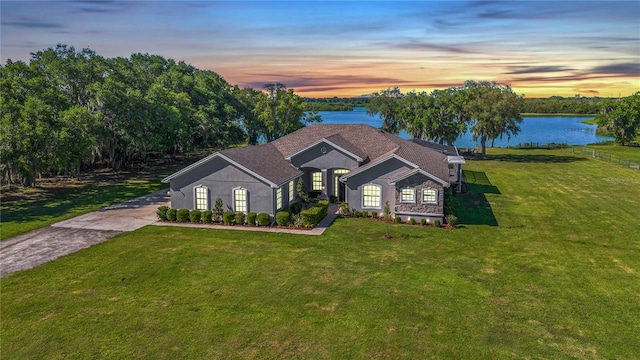 ranch-style home featuring a lawn and a water view