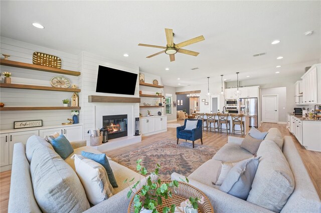 living room with ceiling fan and light hardwood / wood-style flooring