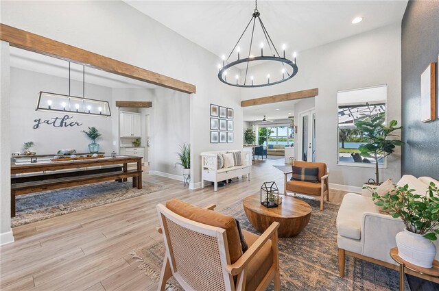 living room featuring ceiling fan with notable chandelier, a towering ceiling, and light hardwood / wood-style flooring