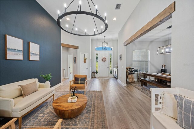 living room featuring light hardwood / wood-style flooring, a towering ceiling, and a chandelier