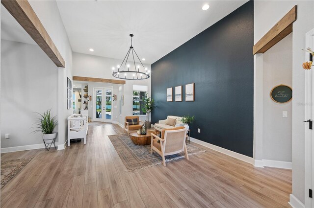 foyer featuring an inviting chandelier, light wood-type flooring, and beamed ceiling