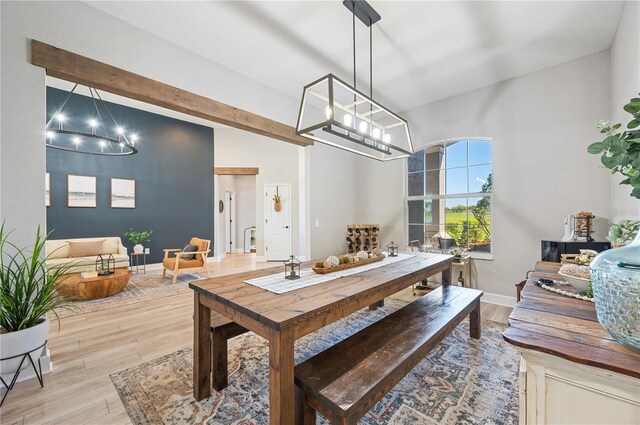 dining space featuring light wood-type flooring, vaulted ceiling with beams, and an inviting chandelier