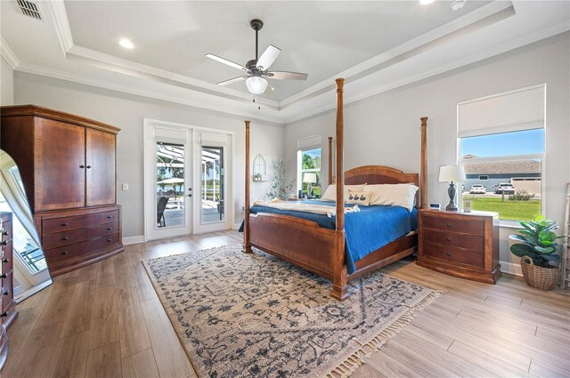 bedroom featuring a raised ceiling, access to exterior, light wood-type flooring, crown molding, and ceiling fan