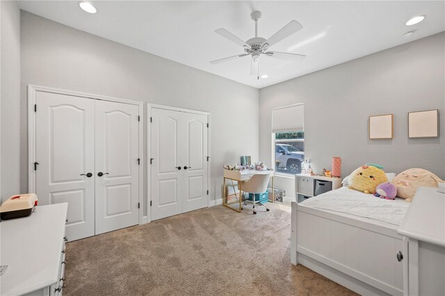 bedroom featuring light carpet, multiple closets, and ceiling fan