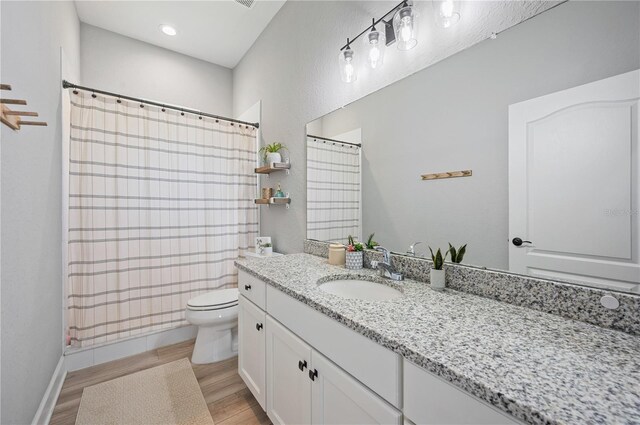 bathroom with hardwood / wood-style floors, walk in shower, vanity, and toilet