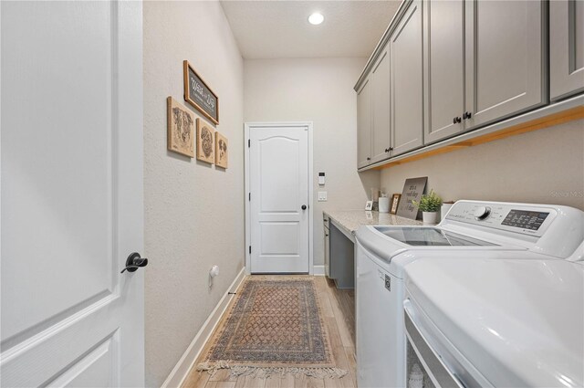 laundry room featuring wood-type flooring, washer and dryer, and cabinets