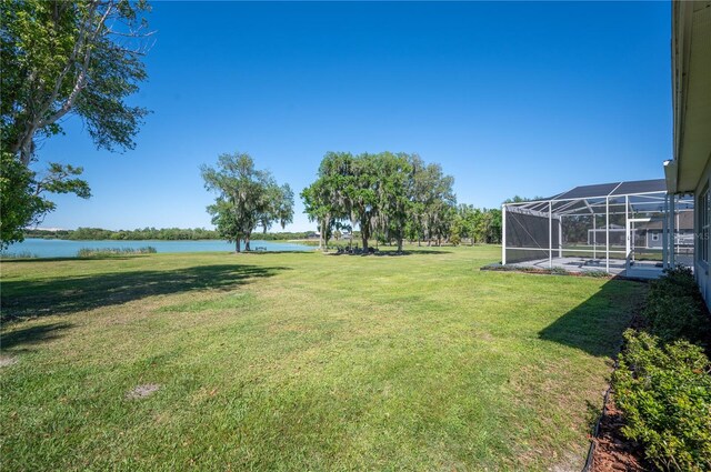 view of yard with a lanai and a water view